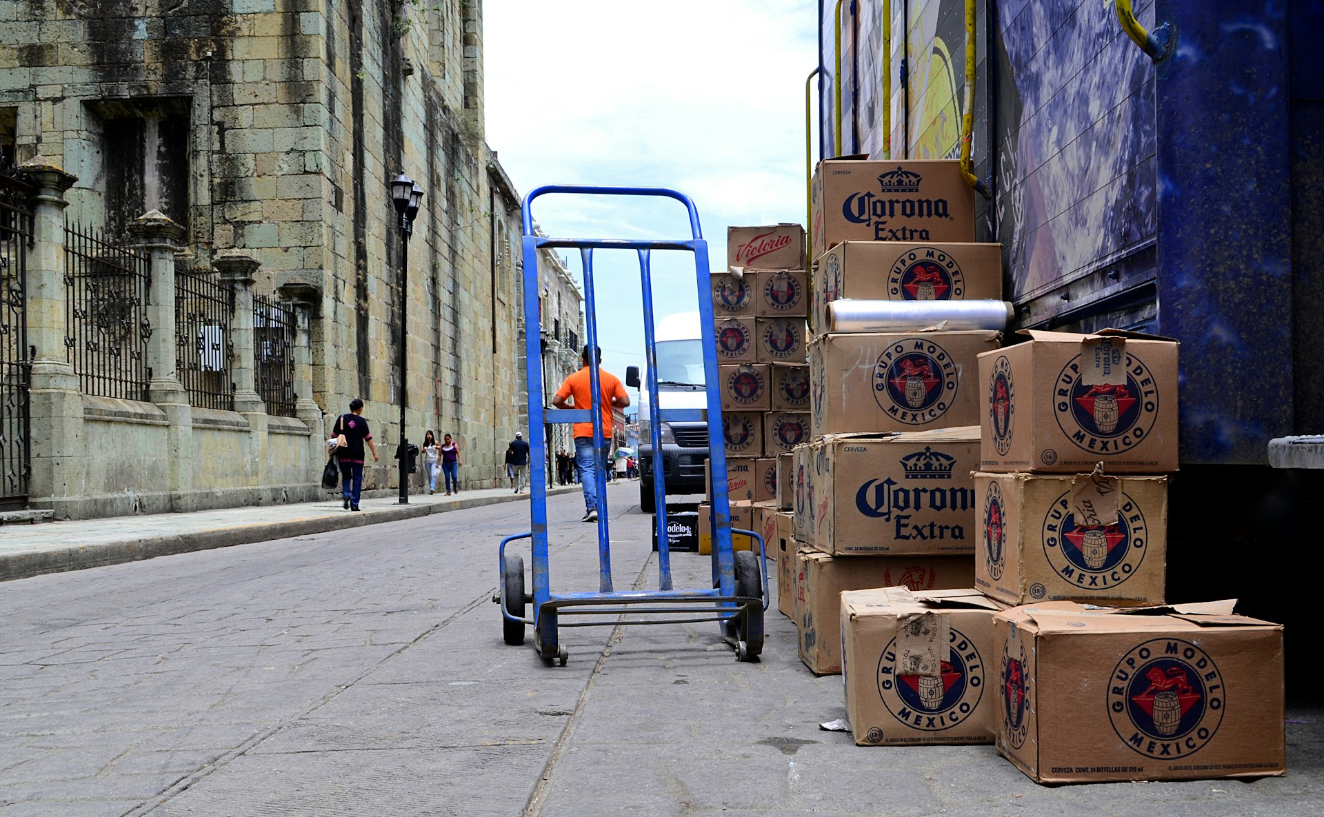 blue hand truck beside cardboard boxes